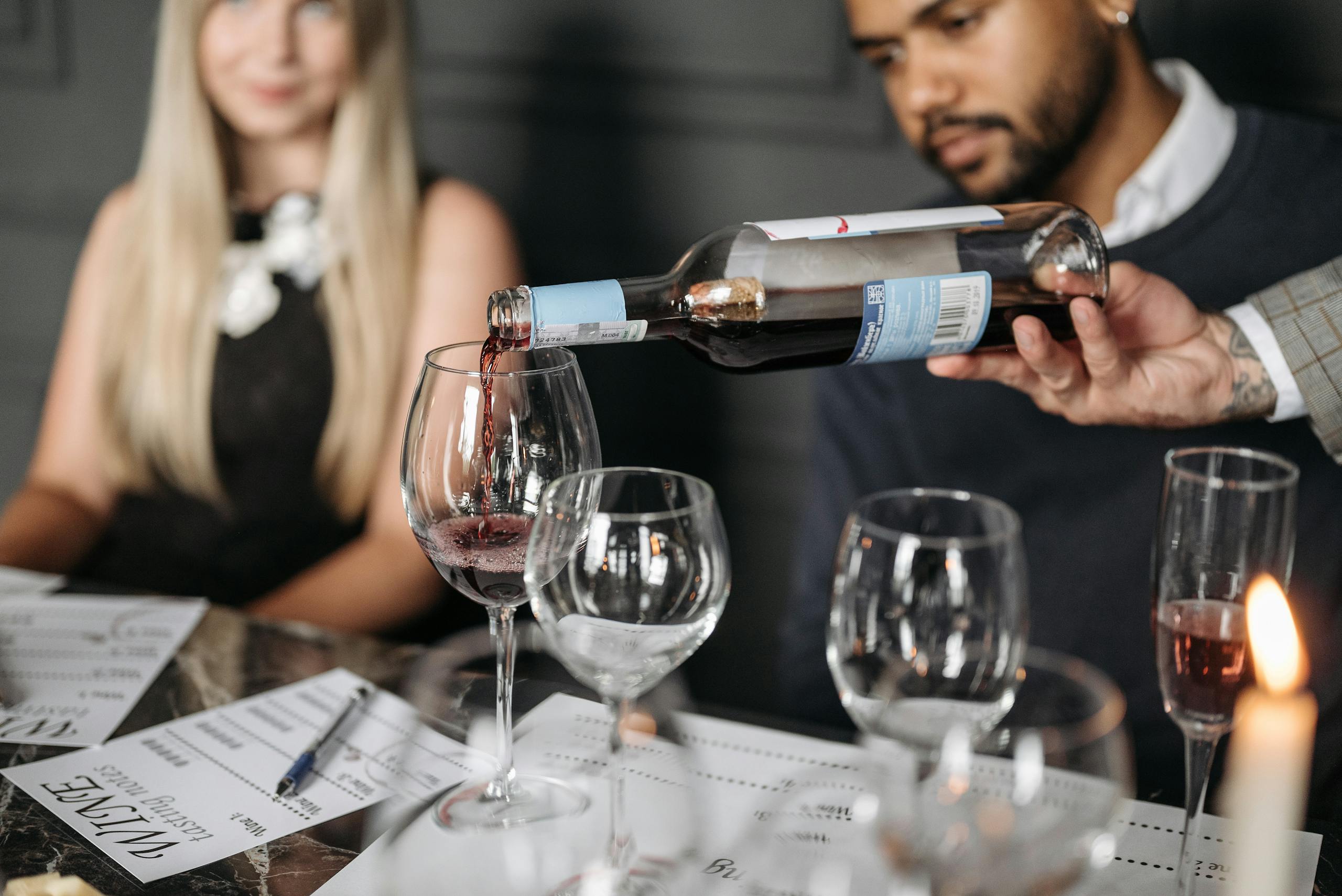 A wine bottle being elegantly poured into a glass during a formal dinner gathering.